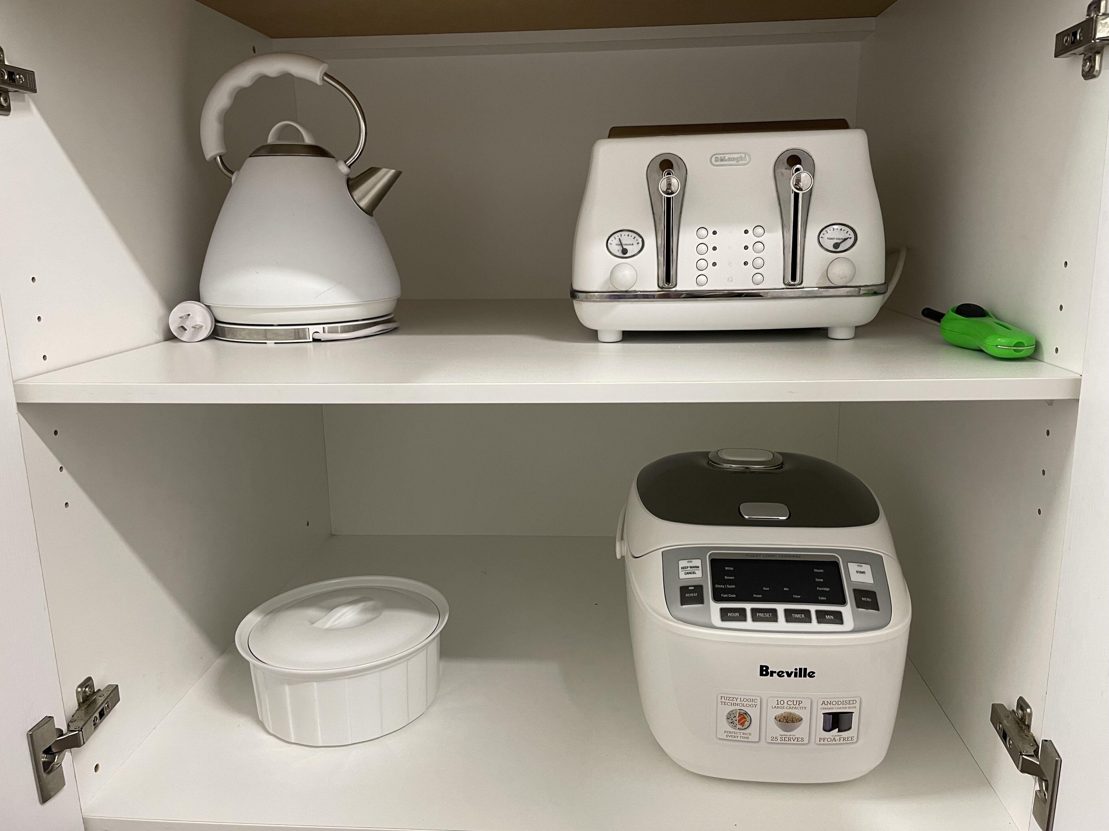 A kitchen with a kettle, toaster, and Breville rice cooker on the shelves.
