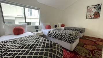 A hotel room with two beds, a window, a nightstand, a lamp, and a patterned carpet.