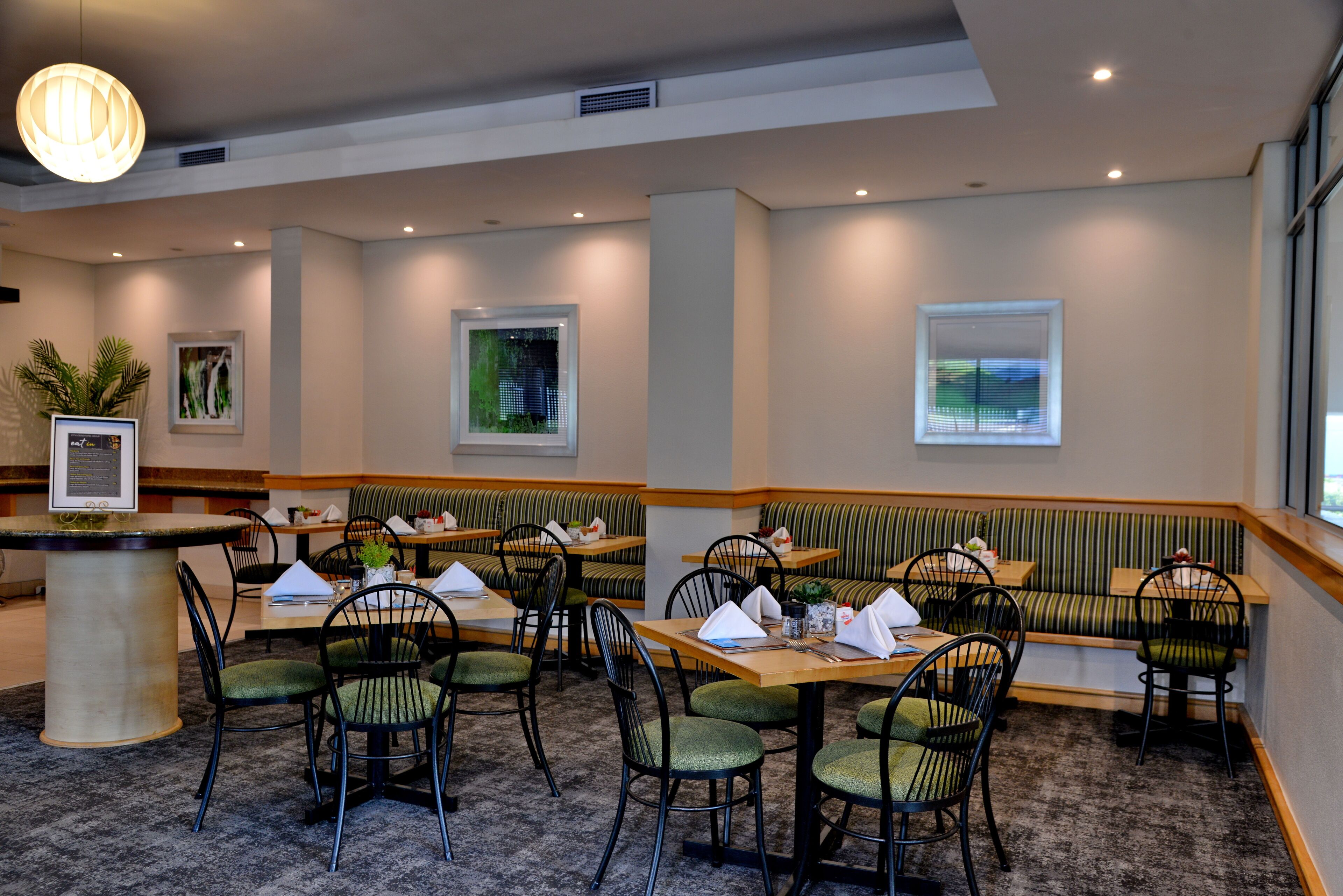 Un restaurante con varias zonas de estar, incluyendo cabinas y mesas, suelo alfombrado y una decoración de interiores moderna.