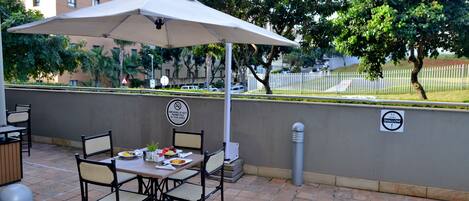 An outdoor patio with a table and chairs, a pool, and a City Lodge Hotel sign in the background.