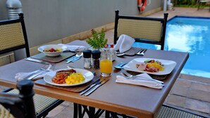 Un tavolo da pranzo apparecchiato con piatti di cibo, posate e un bicchiere di succo d'arancia.