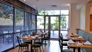 Un ristorante con tavoli e sedie, ampie finestre e vista sull'esterno.