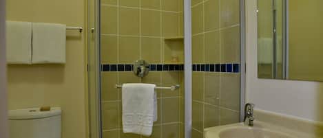 A bathroom with a toilet, a glass-enclosed shower, a sink, and a towel rack.