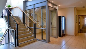 Un interno moderno con una scala, un ingresso con porta in vetro e una macchina distributrice.