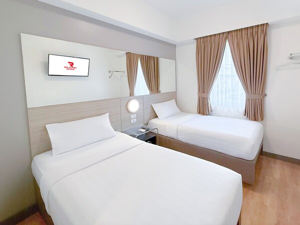 Habitación de hotel con dos camas, un televisor montado en la pared y una ventana con cortinas.