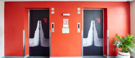 A modern elevator with red walls and a hand symbol on the doors.