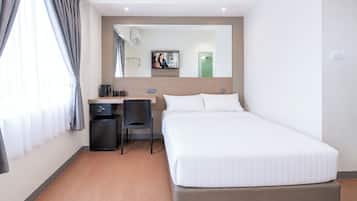 Ein Hotelzimmer mit einem Bett, einem Schreibtisch, einem Stuhl, einem Fernseher und einem Fenster mit Vorhängen.