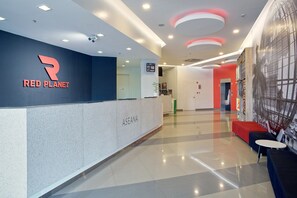 Una recepción moderna con un letrero de 'RED PLANET', la fecha 'JUL 18' y un cartel de 'BIENVENIDOS'.