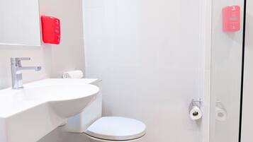 A modern bathroom with a white sink, a toilet, and a glass shower enclosure.