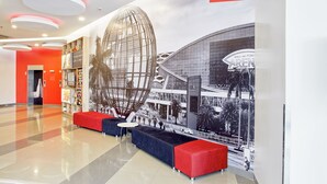Moderni aula, jossa on suuri pallomainen veistos, punaisia ja sinisiä istuimia sekä näkymä Mall of Asia -ostoskeskukseen.
