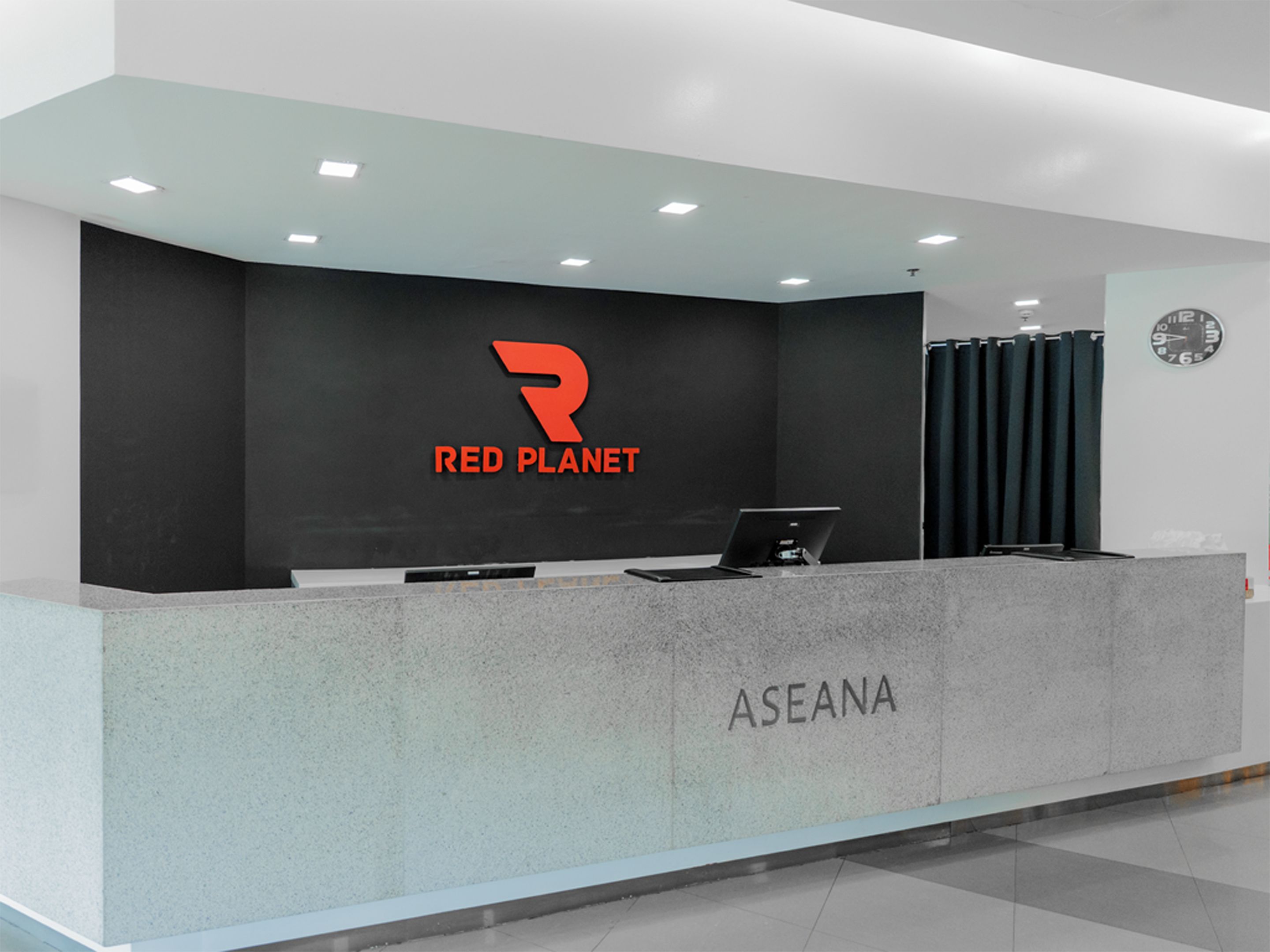 A reception desk with a logo, a clock, and a nameplate.