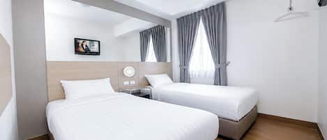 Ein Hotelzimmer mit zwei Betten, einem flachbildfernseher an der Wand und einem Fenster mit Vorhängen.