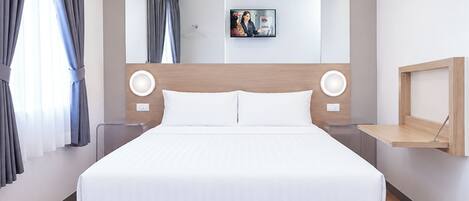Una habitación de hotel moderna con una cama grande, cabecera con iluminación integrada, una mesita de noche y una estantería de pared.