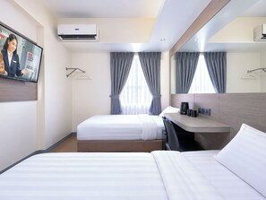 A hotel room with two beds, a desk, a flat-screen TV, and a large mirror.