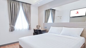 Hotellihuone, jossa on sänky, työpöytä, tuoli, kahvinkeitin ja seinälle asennettu televisio.