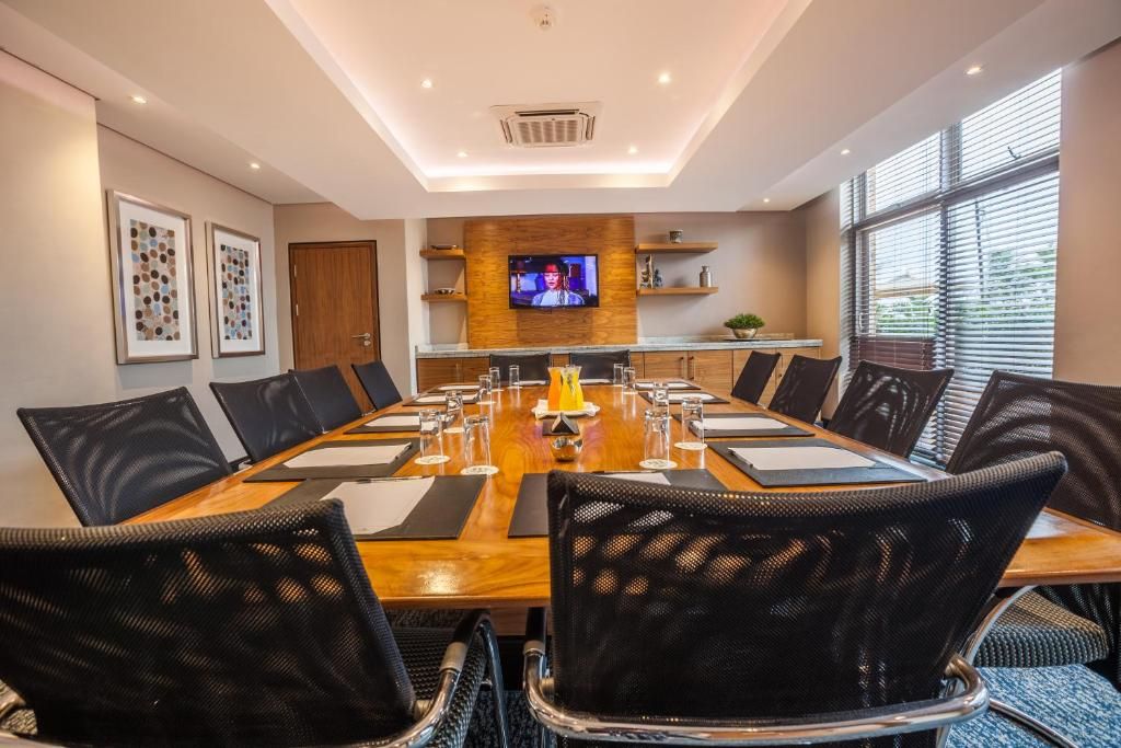 A conference room with a long table, black chairs, a television, and framed artwork on the walls.