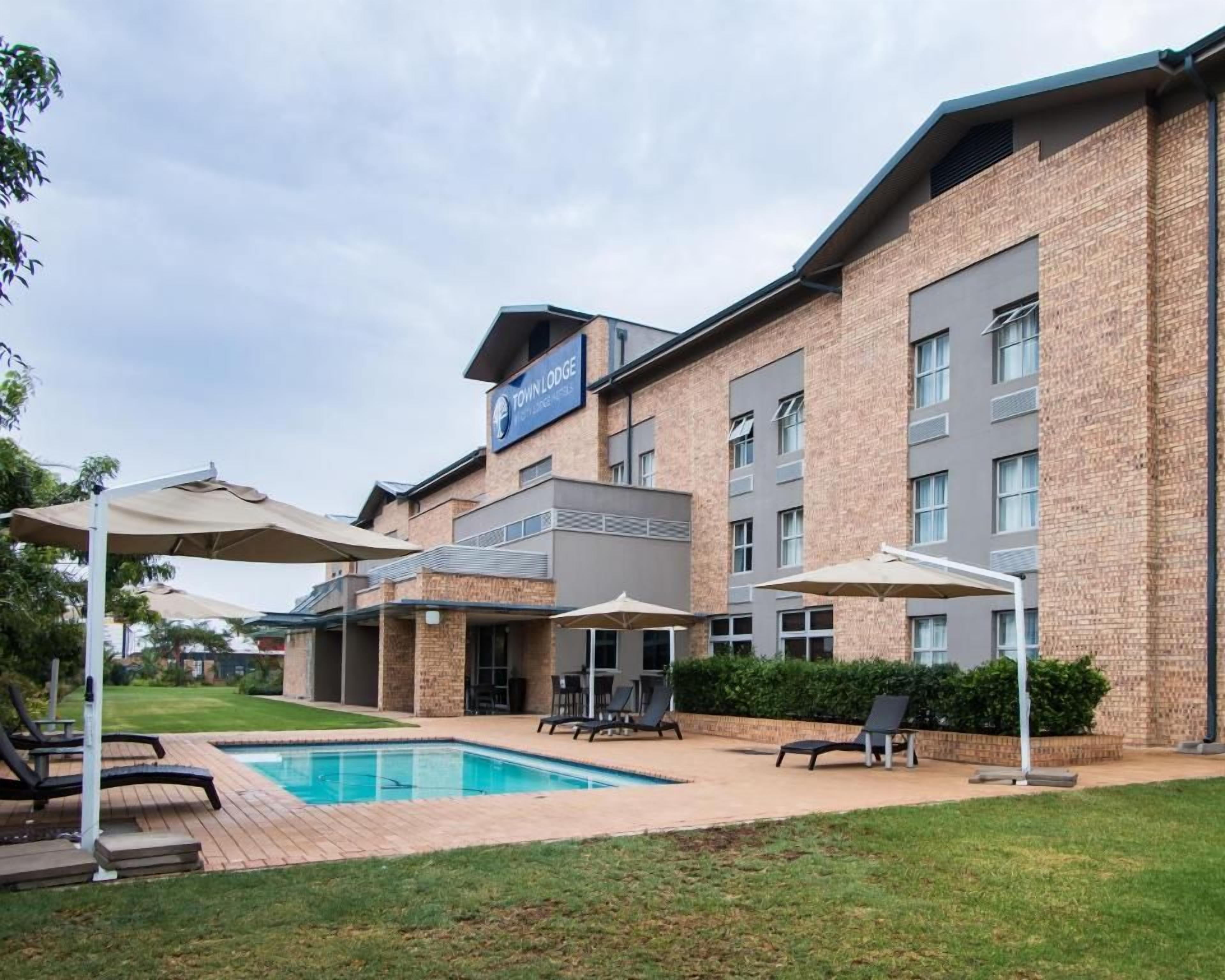 Un hotel con piscina, mobiliario exterior y fachada de ladrillo.