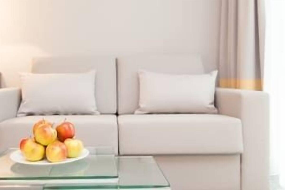 A modern living room with a sofa, a glass coffee table, and a plate of apples.