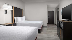 Une chambre d’hôtel avec deux lits, une télévision, un bureau et une armoire.