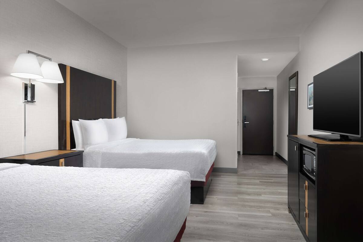 Una habitación de hotel con dos camas, televisión, escritorio y armario.