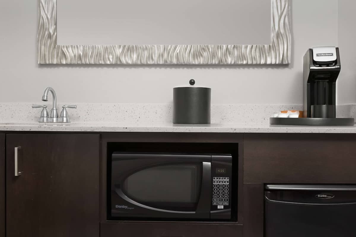 Una cocina con microondas integrado, cafetera y lavavajillas.
