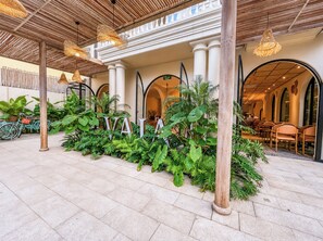 A spacious outdoor area with a tiled floor, surrounded by lush green plants and wooden columns. - Vaia Hoi An Boutique Hotel (Da Nang)