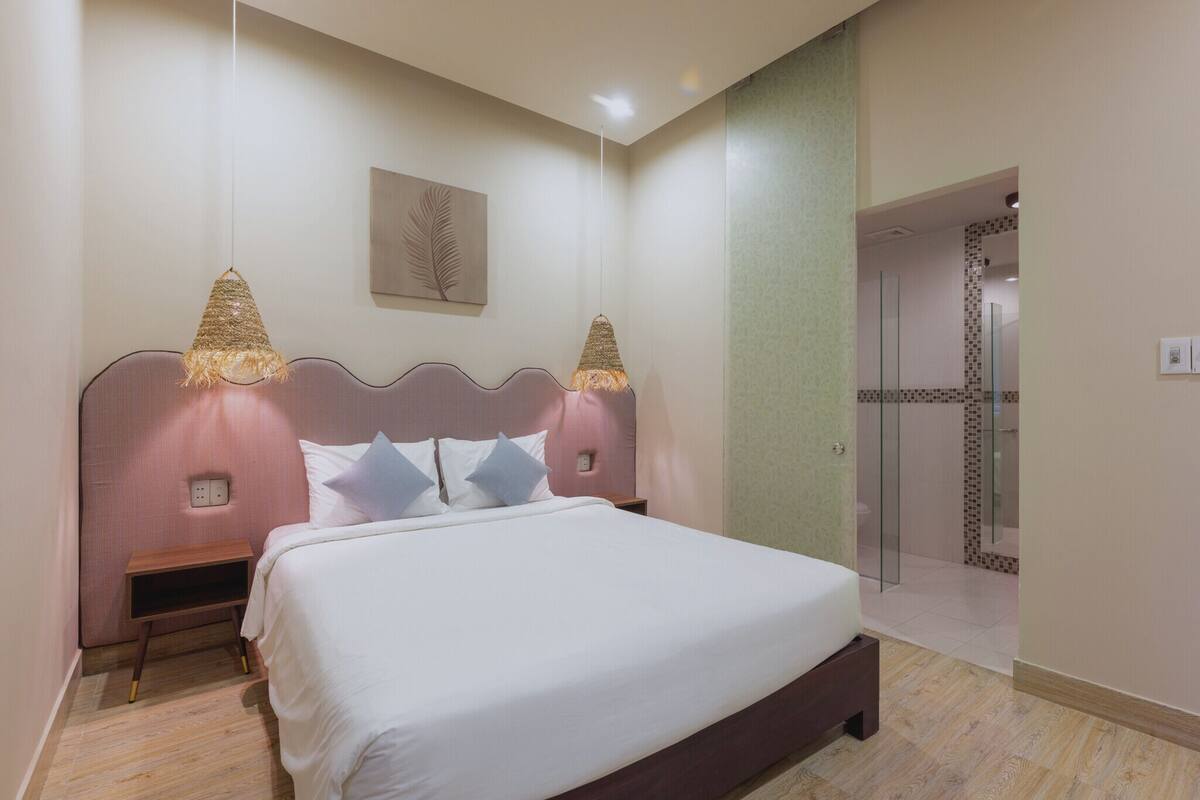 Un dormitorio con cama, mesitas de noche y zona de ducha.