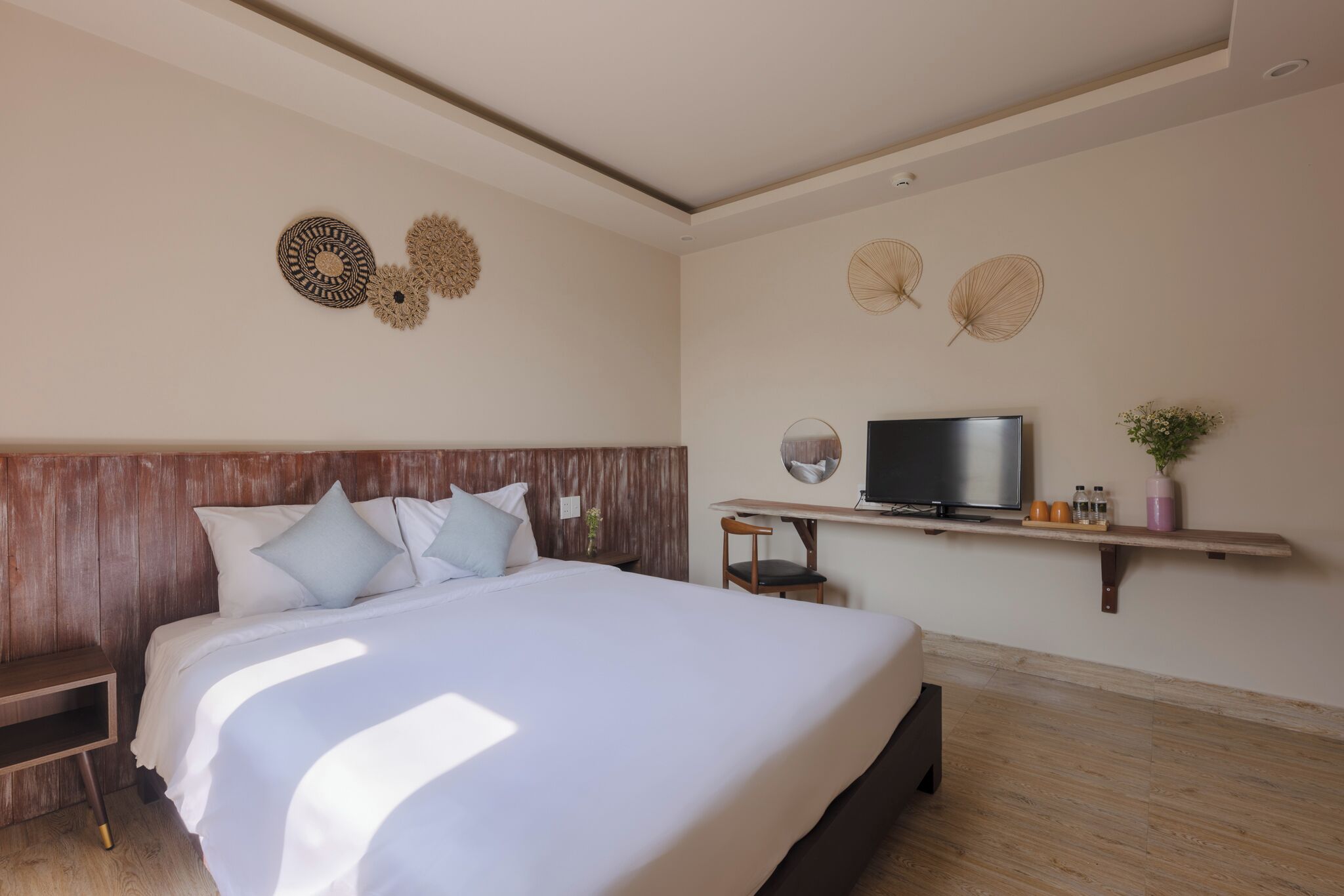 A bedroom with a large bed, wooden headboard, a TV, and wall decor.