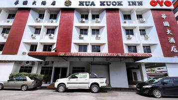 A hotel with a red and white facade, multiple air conditioning units, and a covered entrance.