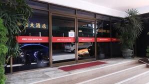 A hotel entrance with glass doors, a red mat, and a potted plant. - Hotel O Hua Kuok Inn (Kuching)