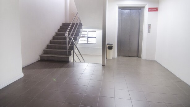 A clean, modern interior with a staircase, a trash bin, and an elevator. - Hotel O Hua Kuok Inn (Kuching)
