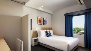 A hotel room with a bed, a desk, a chair, a nightstand, and two framed pictures on the wall. - Four Points Flex By Sheraton Tokyo Ueno (Tokyo)