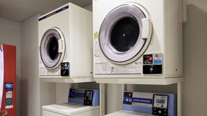 A laundry facility with two front-loading washing machines and two stacked dryers. - Four Points Flex By Sheraton Tokyo Ueno (Tokyo)