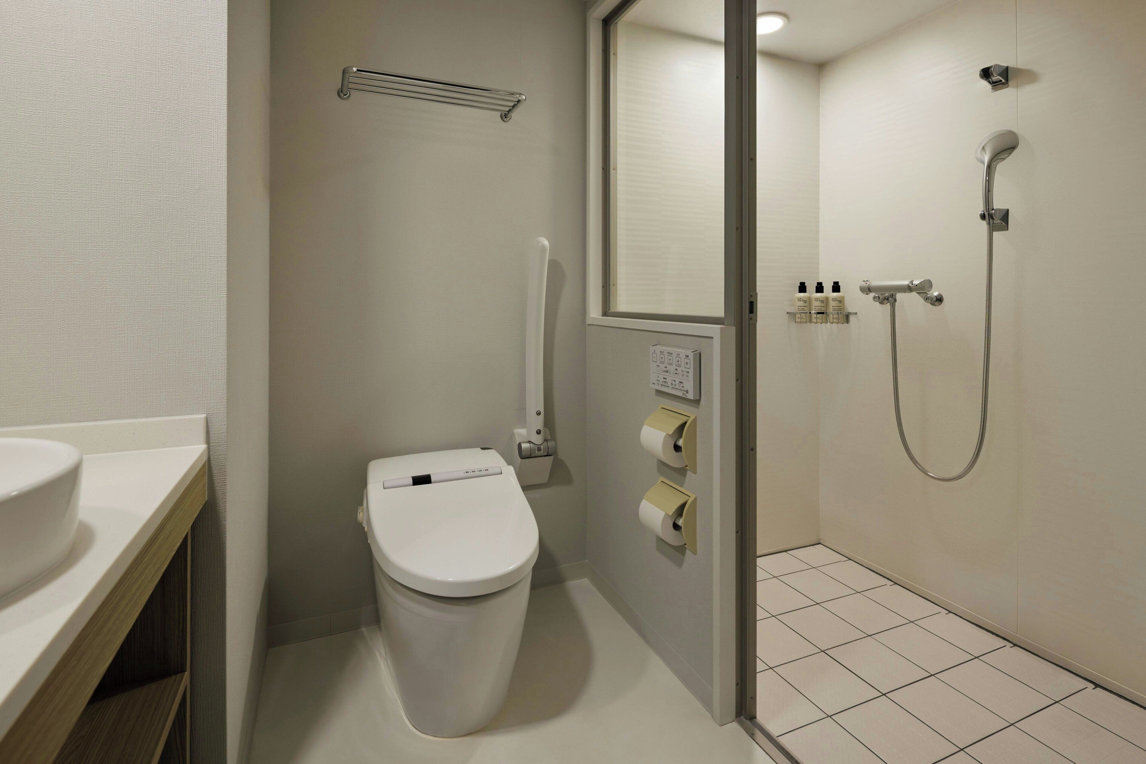 Une salle de bain moderne équipée de toilettes, d’une douche et d’un lavabo.