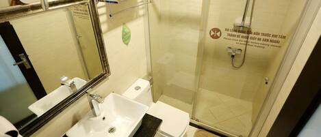 Un baño con lavabo, inodoro y ducha con mampara de vidrio.