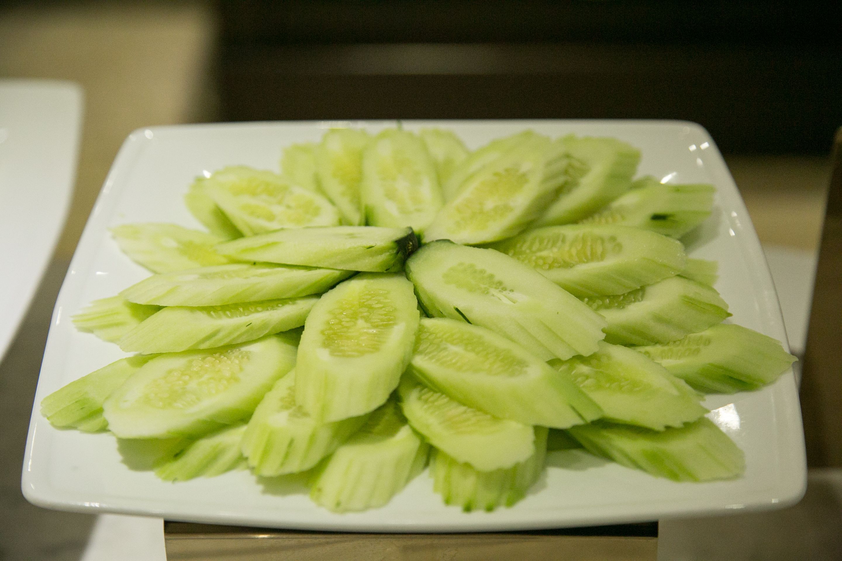 A white plate with neatly arranged cucumber slices.