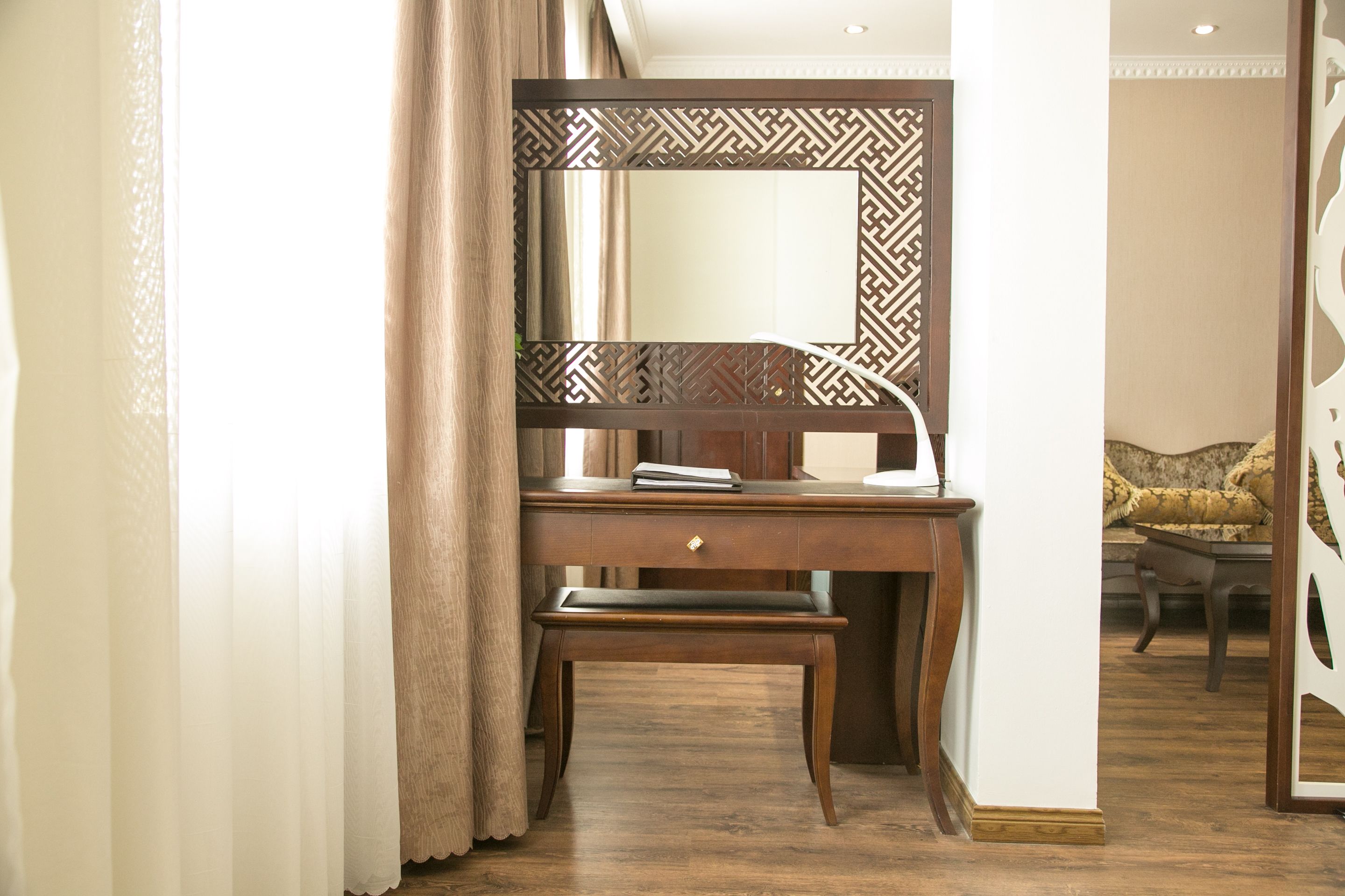 A wooden desk with a mirror, a book, and a lamp.