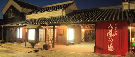 A traditional Japanese building with a tiled roof and a red entrance gate.