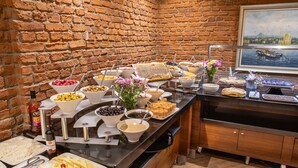 Un bufé con diferentes opciones de comida y un muro de ladrillo al fondo.