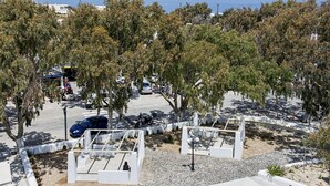 A parking area with trees, a blue car, and a motorcycle.