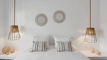 Une chambre à coucher bien rangée, avec un lit, deux lampes suspendues et des coussins décoratifs.