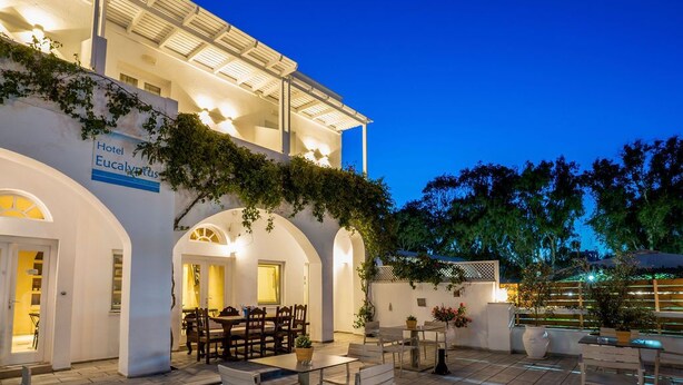 A hotel with a white facade, arched doorways, and outdoor seating areas.