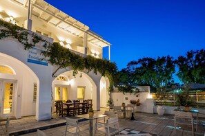 A hotel with a white facade, arched doorways, and outdoor seating areas. - Hotel Eucalyptus (Santorini)