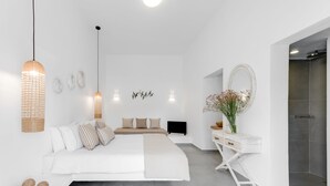 A modern bedroom with a large bed, bedside tables, a desk, and a shower.