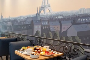 A dining table with breakfast items and a view of the Eiffel Tower through a window. - Hôtel Helussi (Paris)
