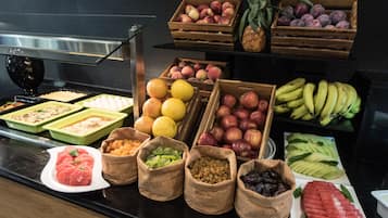 A buffet with various fruits and vegetables, including apples, bananas, and watermelon.