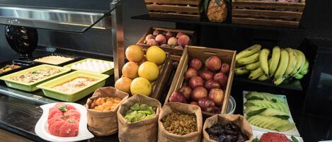 A buffet with various fruits and vegetables, including apples, bananas, and watermelon.