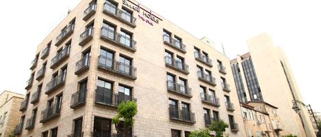 A multi-story building with balconies, a sign reading "SIMAR HOEIS," and a modern architectural style.