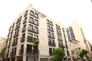 Un edificio de varios pisos con balcones, un letrero que dice "SIMAR HOEIS" y un estilo arquitectónico moderno.