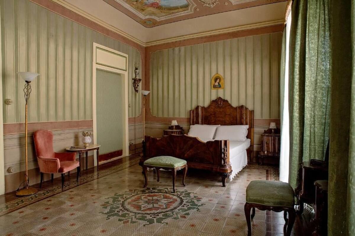Een kamer met een bed, een stoel, een klein tafeltje en een decoratief vloerkleed.
